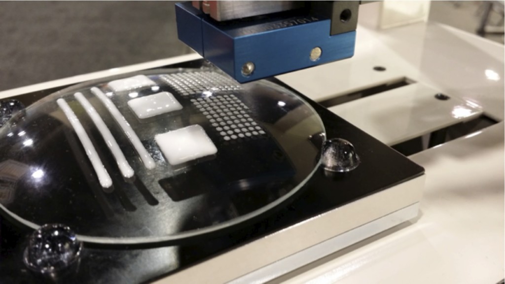 The Aerojet printing a pattern onto a curved glass surface. It can 3D print thin lines, tiny droplets, and solid shapes.